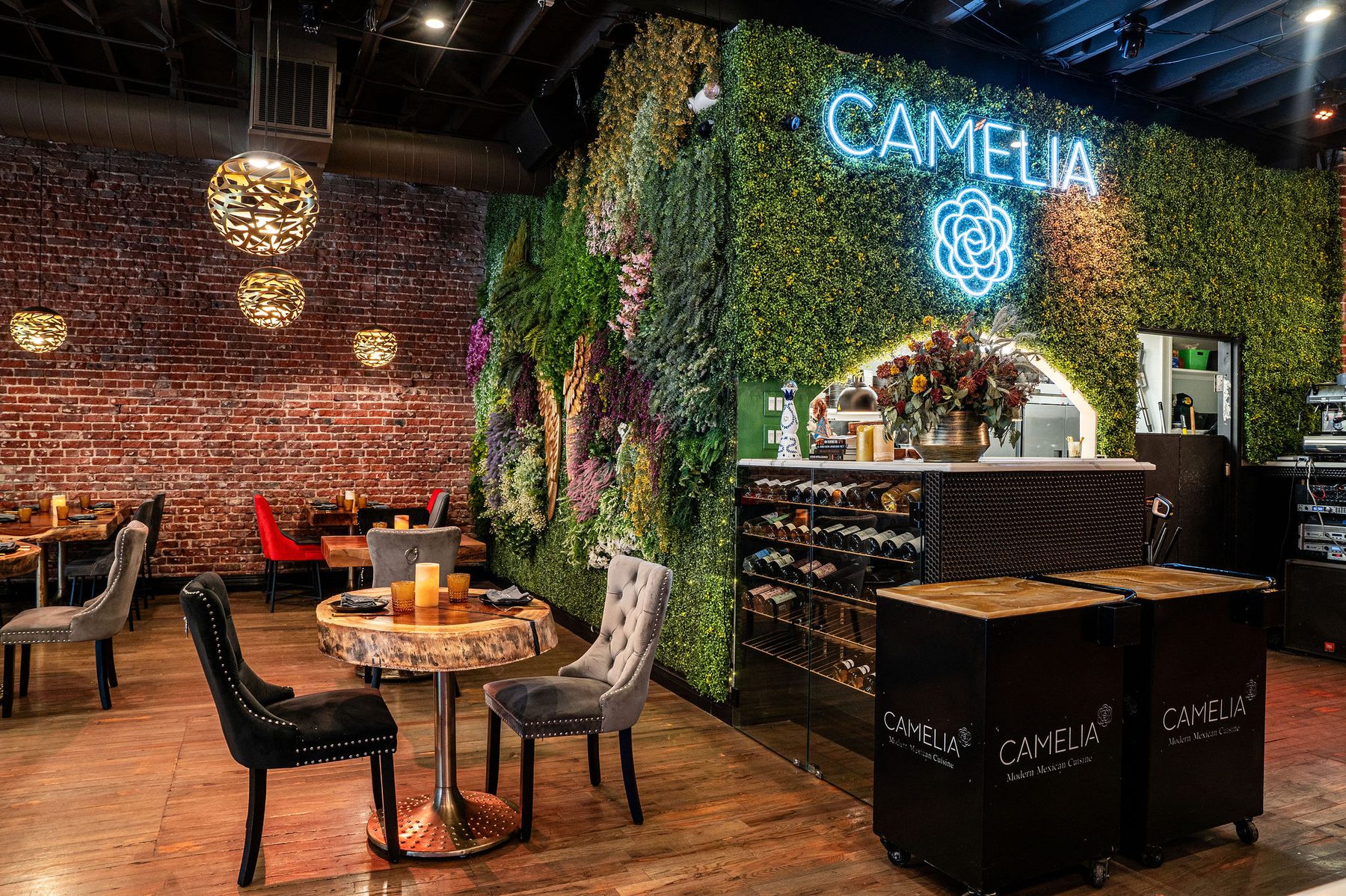 Camelia dining room — living green wall with neon CAMELIA sign, exposed brick, gold pendant lighting